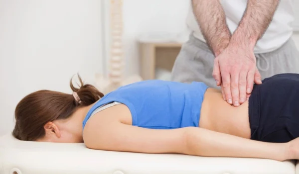 A woman is getting her back examined by an osteopath.
